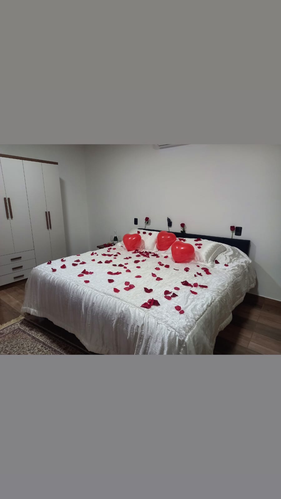Quarto romântico com pétalas de rosa e balões em formato de coração